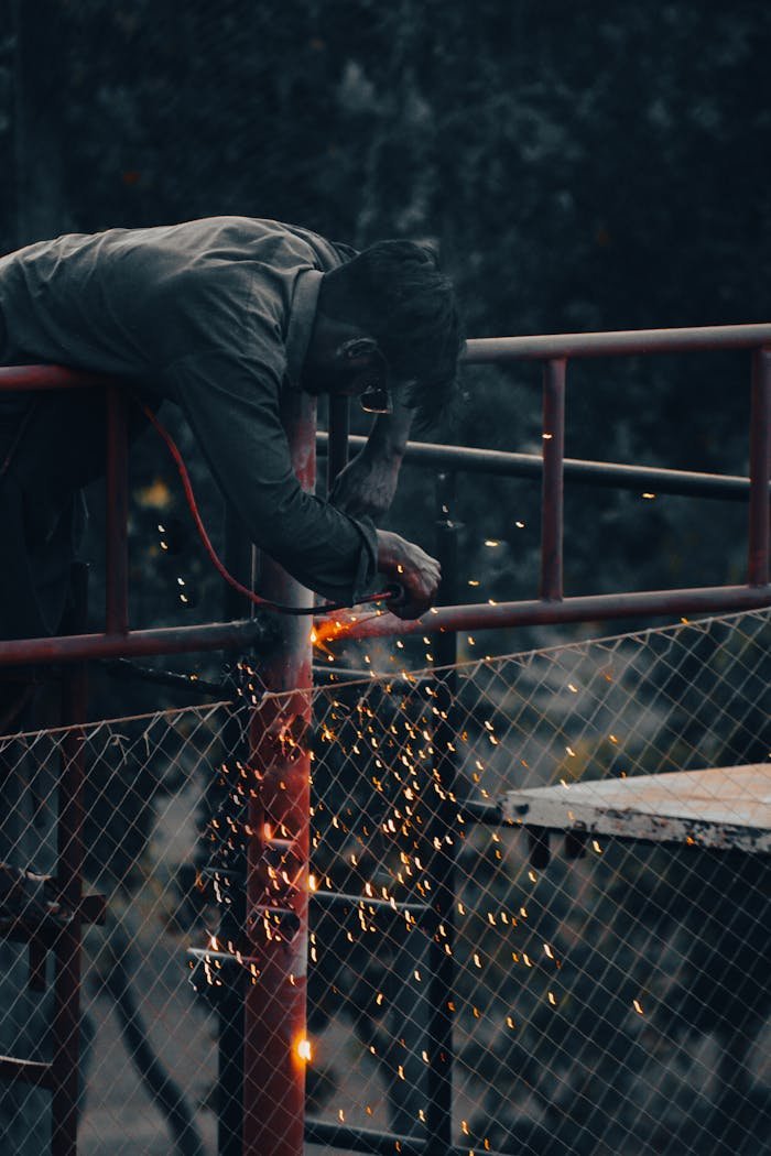 Industrial worker welding metal pipes with sparks in Karachi, Pakistan.