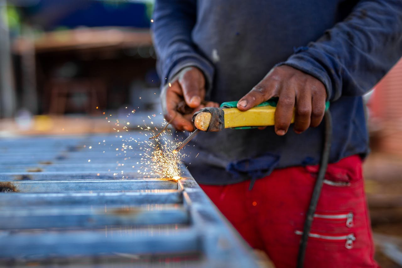 A welder working on metal, creating bright welding sparks in an industrial setting.