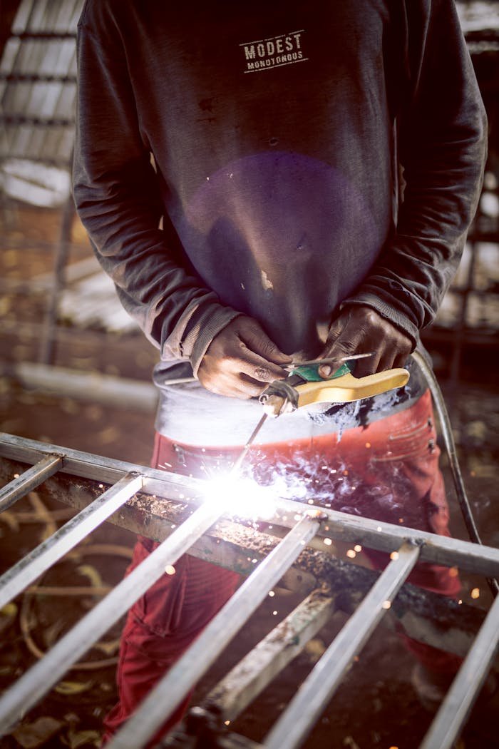A welder skillfully joins metal pieces with bright sparks in an industrial workshop.