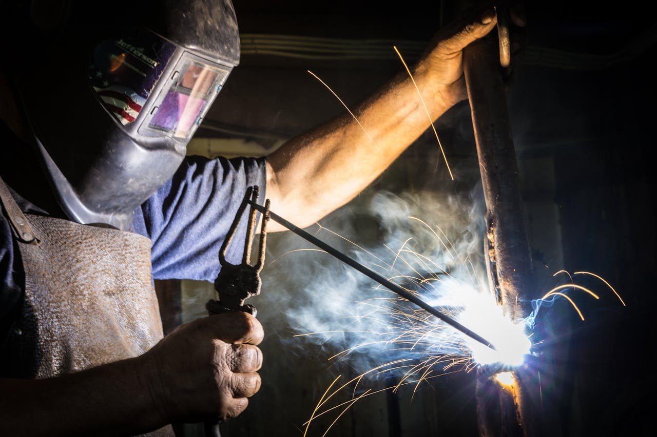 Close-up of a welder in action, showcasing bright sparks and metalworking skill indoors.